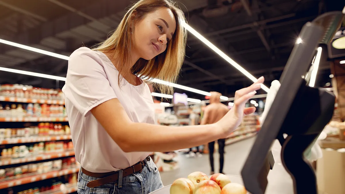 woman paying at a grocery self-checkout with produce